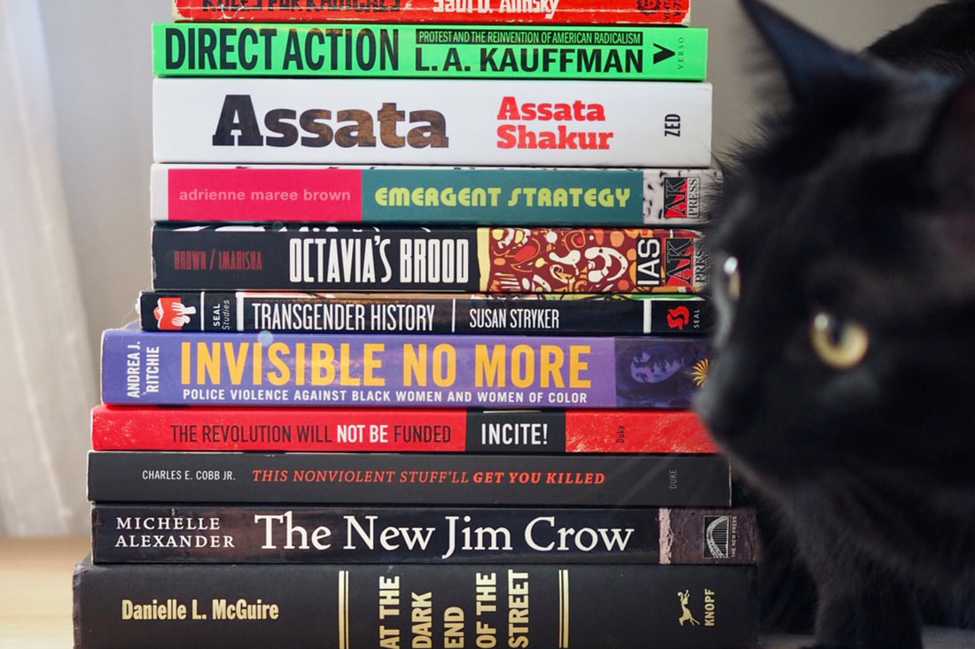 a photo of a stack of books with a black cat to the right
